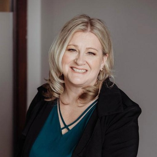 A woman standing in front of a wall smiling.